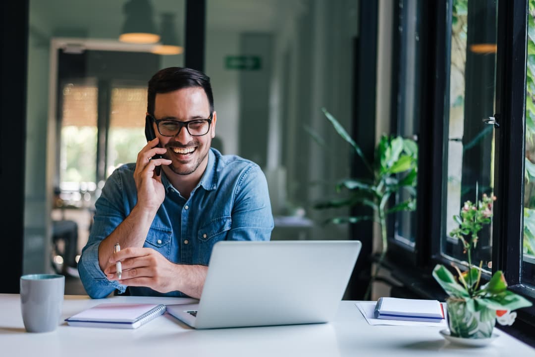 Estudiante feliz trabajando con laptop y teléfono